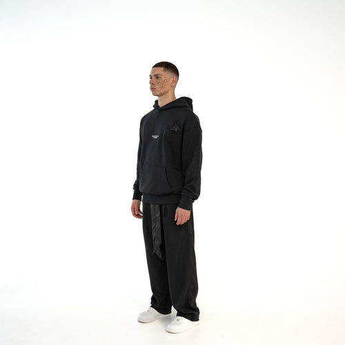 TenProcentr BASTILLE Heavyweight Hoodie 500 GSM in Schwarz, seitlich-schraege Vorderansicht am Model, oversized Schnitt