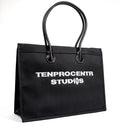 TenProcentr DIX Canvas Tote Bag in Schwarz, Dreiviertelansicht mit TENPROCENTR STUDIOS Stickerei und Lederhenkeln