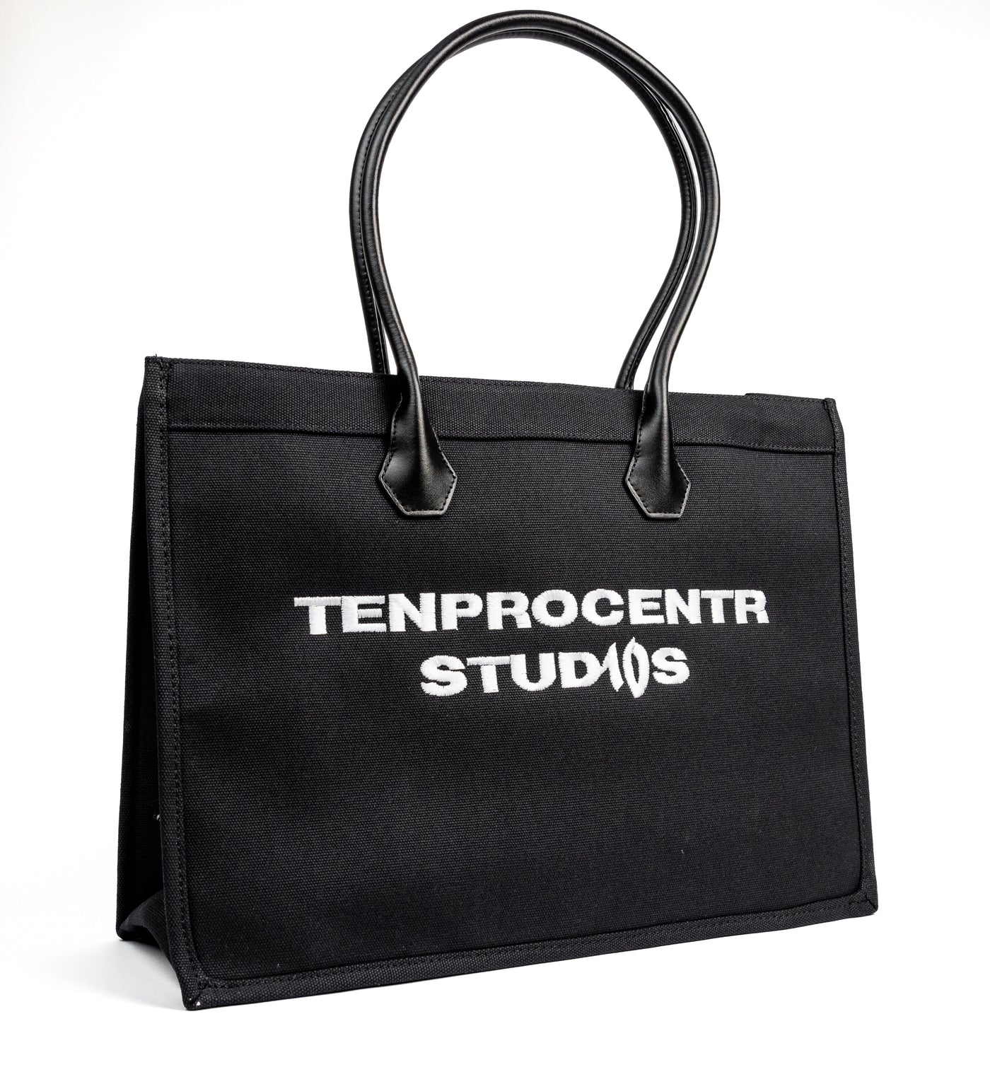 TenProcentr DIX Canvas Tote Bag in Schwarz, Dreiviertelansicht mit TENPROCENTR STUDIOS Stickerei und Lederhenkeln