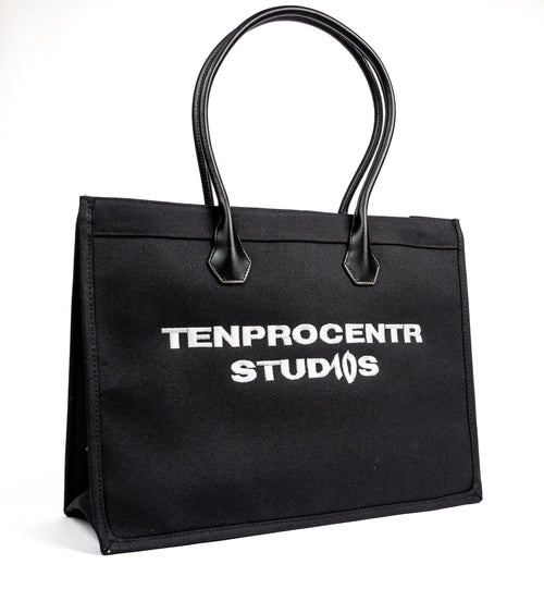 TenProcentr DIX Canvas Tote Bag in Schwarz, Dreiviertelansicht mit TENPROCENTR STUDIOS Stickerei und Lederhenkeln