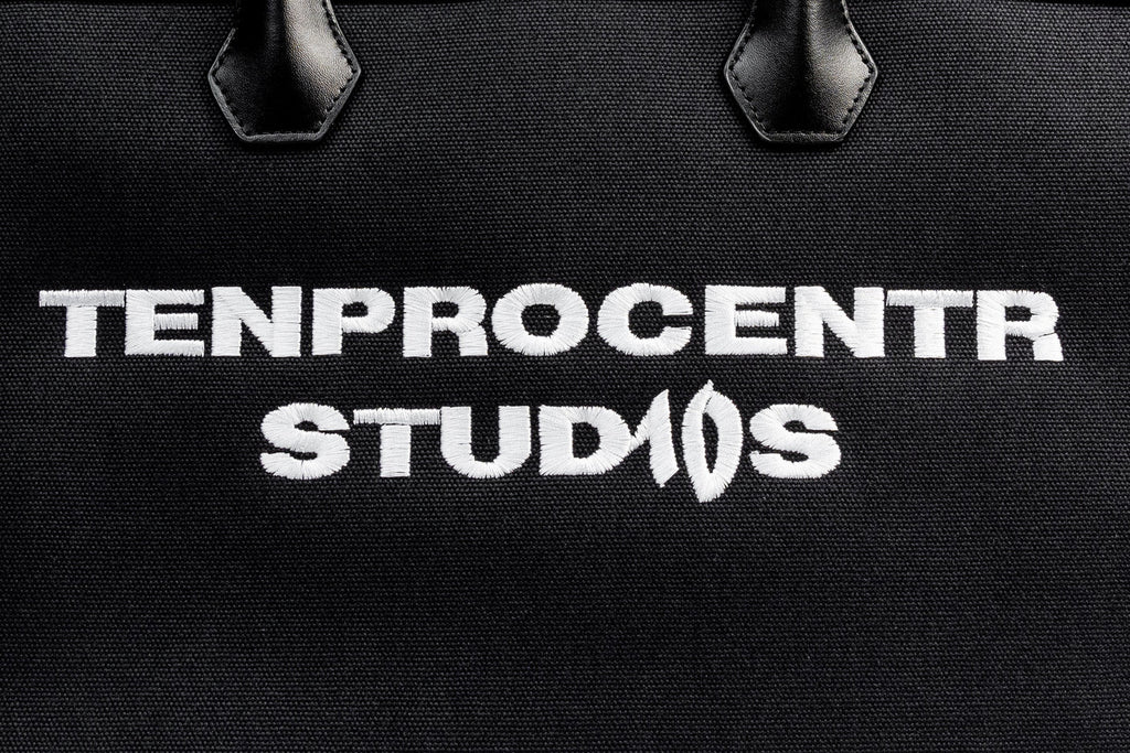 TenProcentr DIX Canvas Tote Bag, Nahaufnahme der gestickten TENPROCENTR STUDIOS Lettering auf schwarzem Canvas