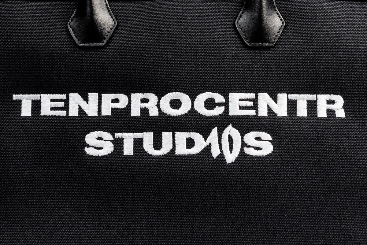 TenProcentr DIX Canvas Tote Bag, Nahaufnahme der gestickten TENPROCENTR STUDIOS Lettering auf schwarzem Canvas