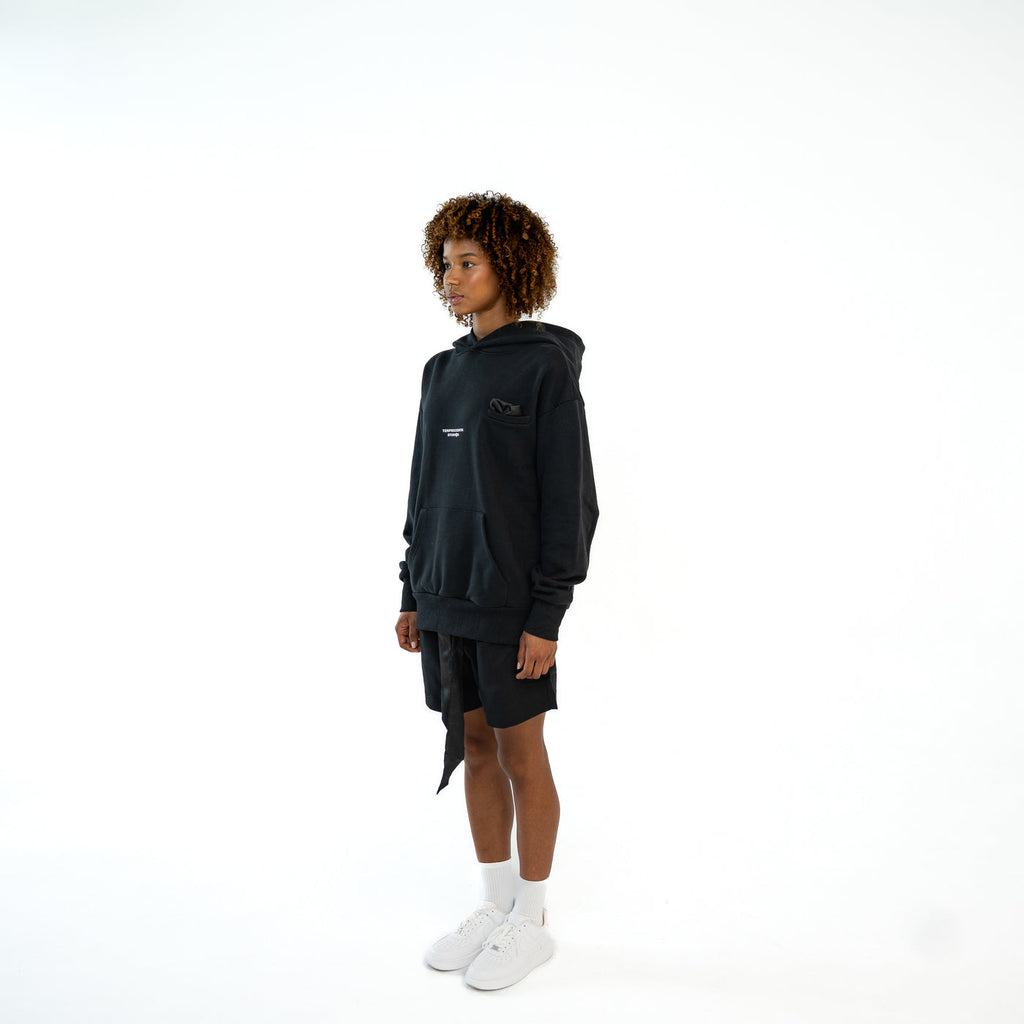 TenProcentr EN MARGE Heavyweight Hoodie schwarz, getragen in leichter Seitenansicht mit Kängurutasche
