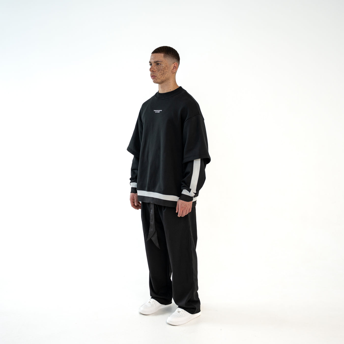 TenProcentr MUR Double-Layer Sweater in Schwarz, seitliche Dreiviertelansicht am Model mit weissen Streifendetails am Arm