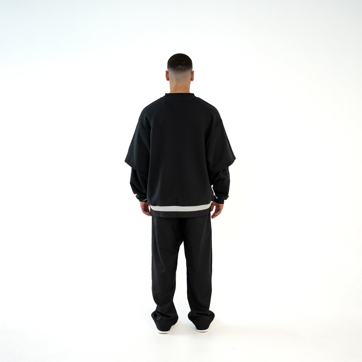 TenProcentr MUR Double-Layer Sweater in Schwarz, Rueckansicht am Model mit weissem Saumstreifen und oversized Passform