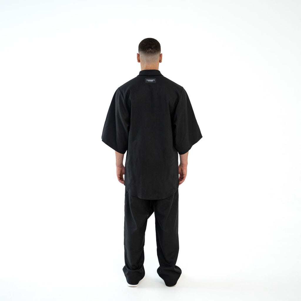 Rückansicht des schwarzen TenProcentr OUTFIELD Oversized Shirts am Model mit TenProcentr Studios Label am Nacken