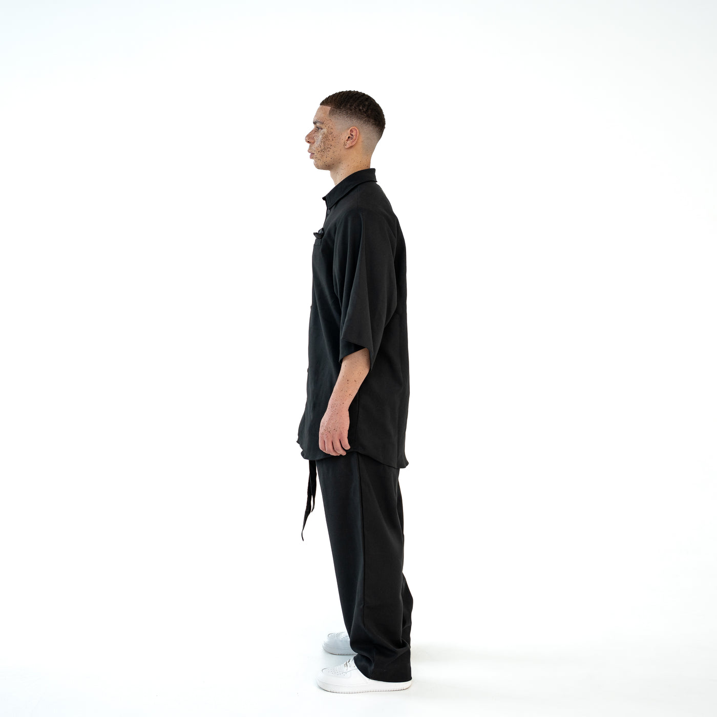 Seitenansicht des schwarzen TenProcentr OUTFIELD Oversized Shirts am Model, betont die oversized Passform und Ärmellänge