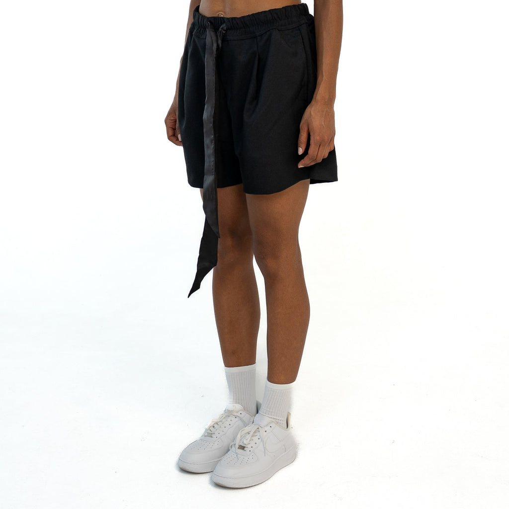 TenProcentr VALLET Tailored Shorts en noir, vue de côté en trois quarts sur mannequin avec ruban en satin retombant